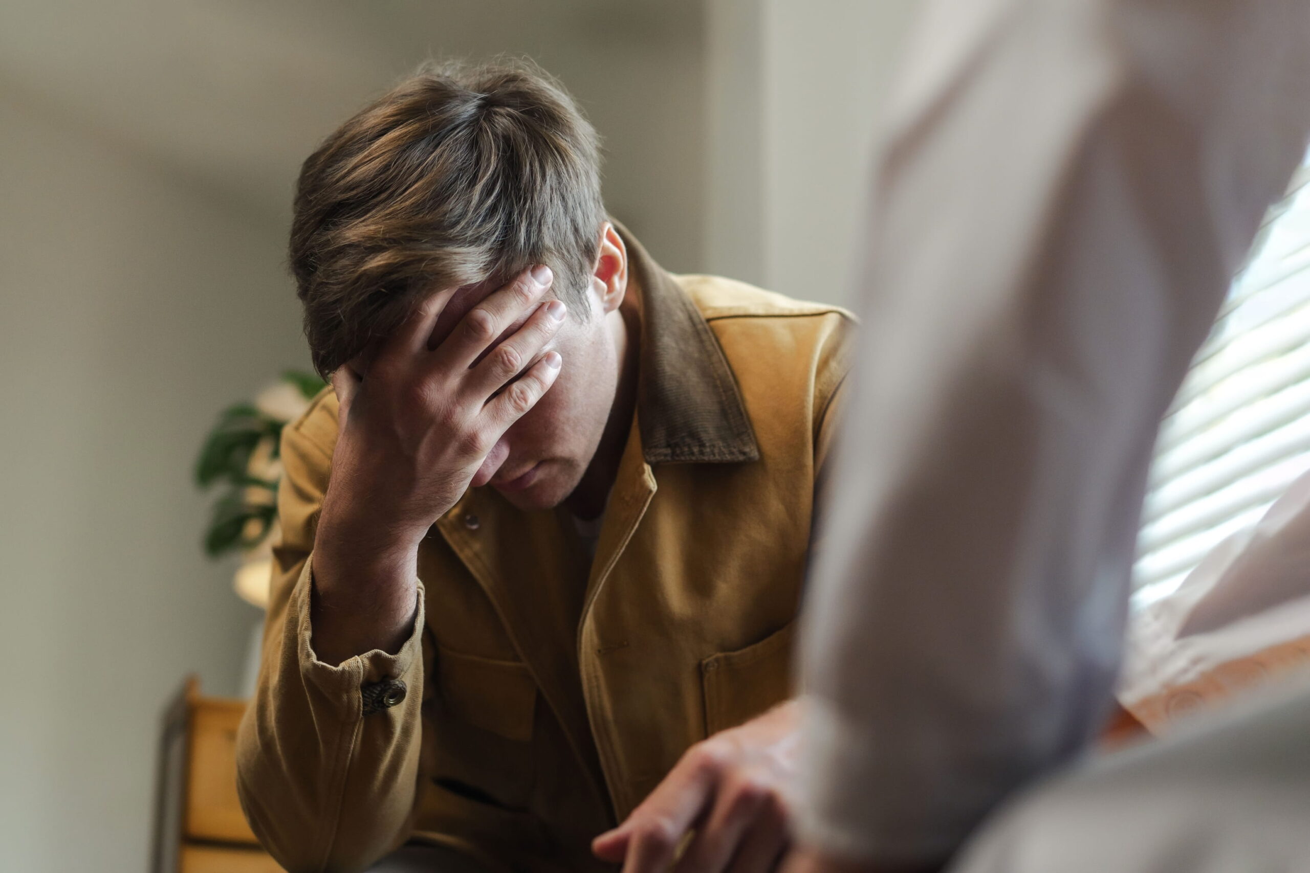 Male patient in couneslor's office leaned over in anguish